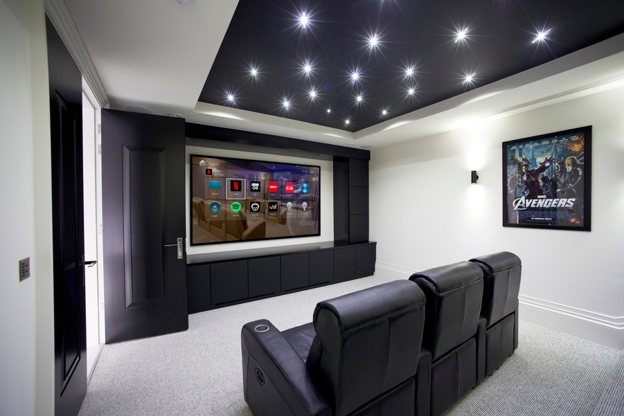a media room with black recliners and tunable lights
