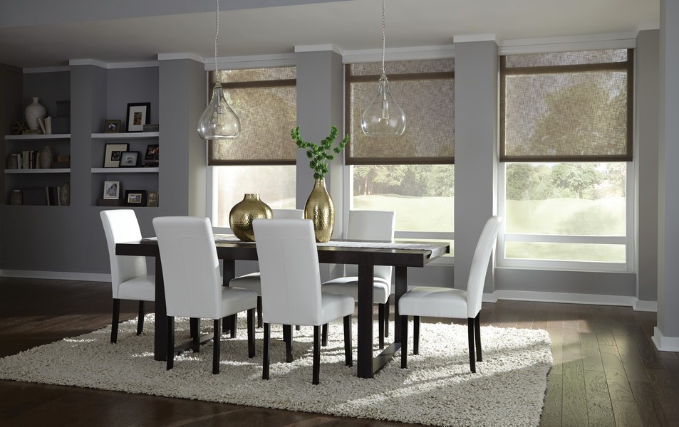 Dining room with dark wood table and white seating facing three windows with black sheer shades. 