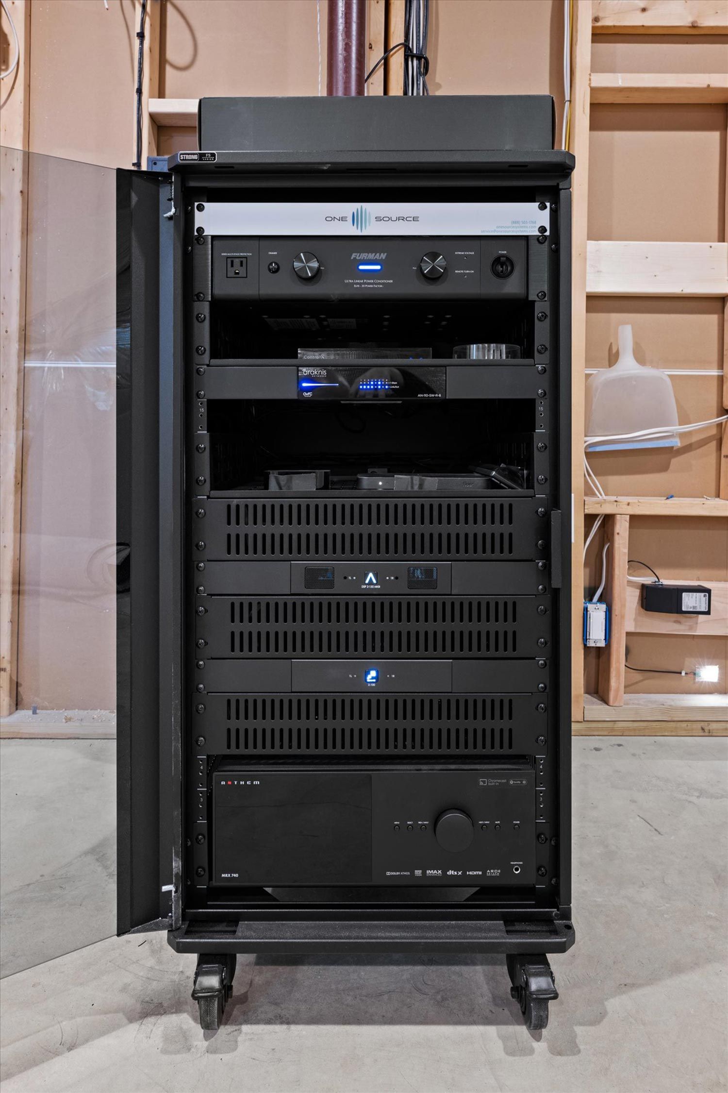 High-end equipment rack in a home theater system setup, showcasing various audio and video components neatly arranged in a black cabinet.