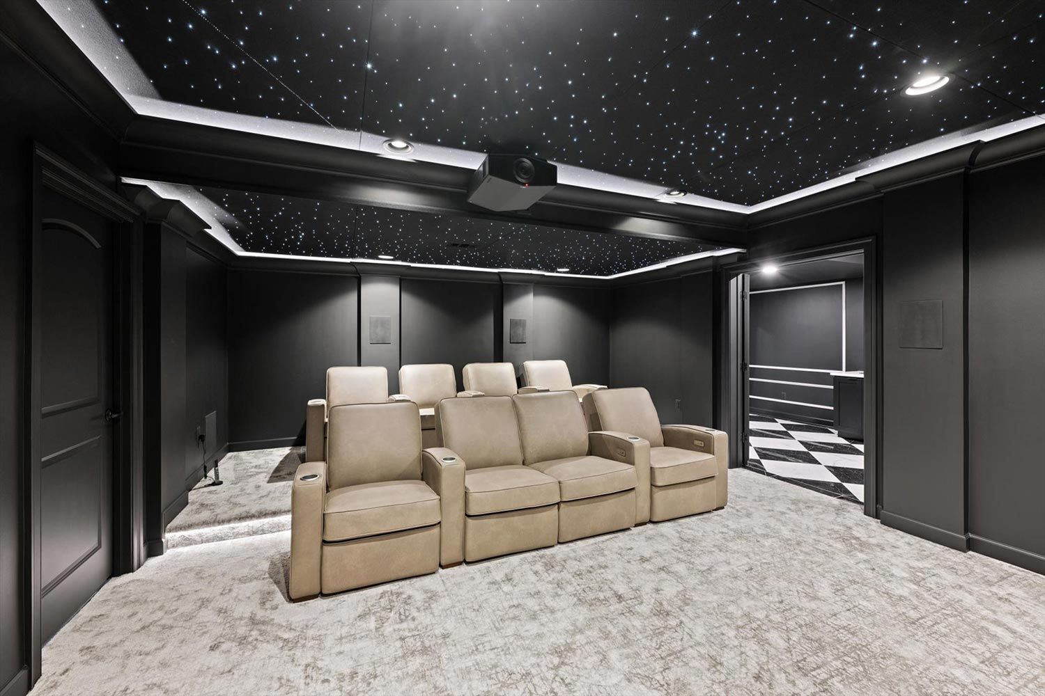 Luxurious home theater featuring plush reclining seats arranged in rows, all under a ceiling designed to look like a starry night sky with tiny LED lights.