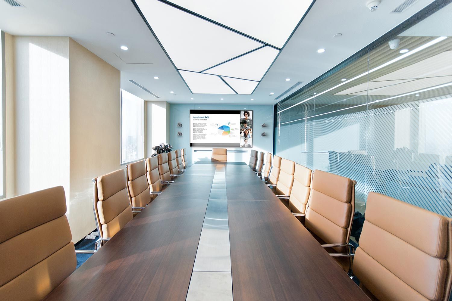 A modern conference room with a long wooden table, tan leather chairs, and a large screen displaying a presentation.