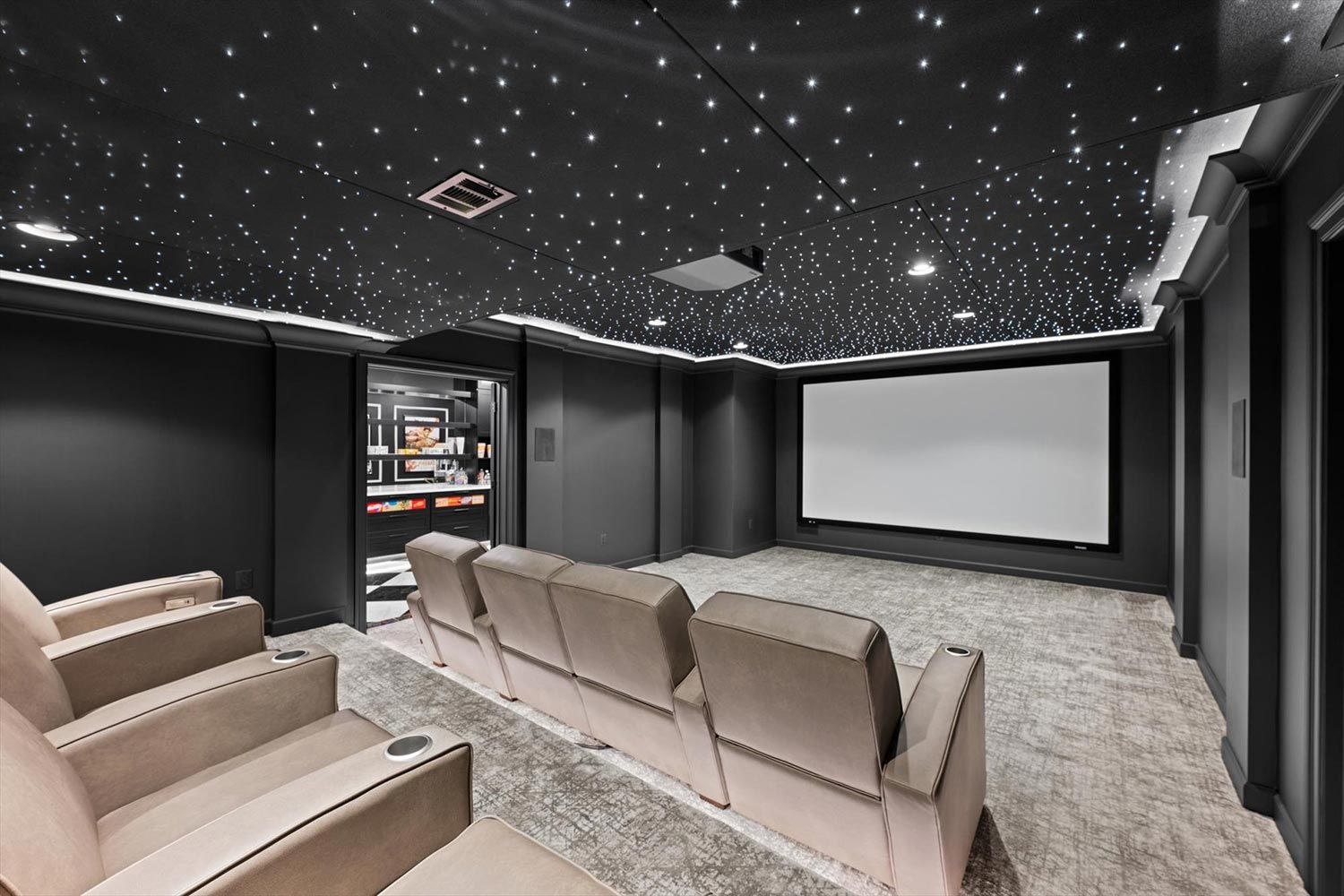 Elegant home theater room with multiple rows of seating and a view into a concession area, all under a starry ceiling, blending comfort and convenience.