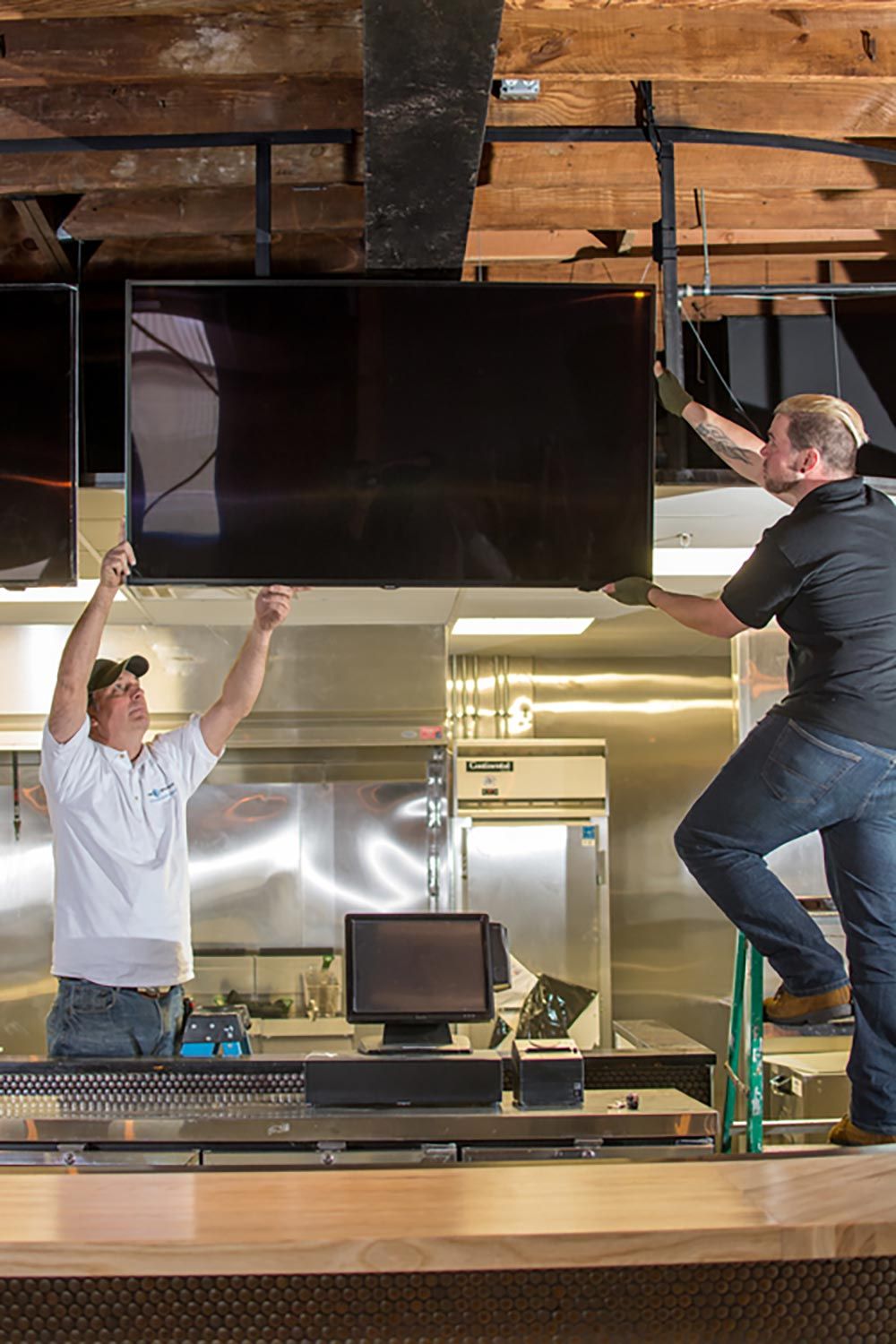 One Source Project Managers hanging a TV in a kitchen