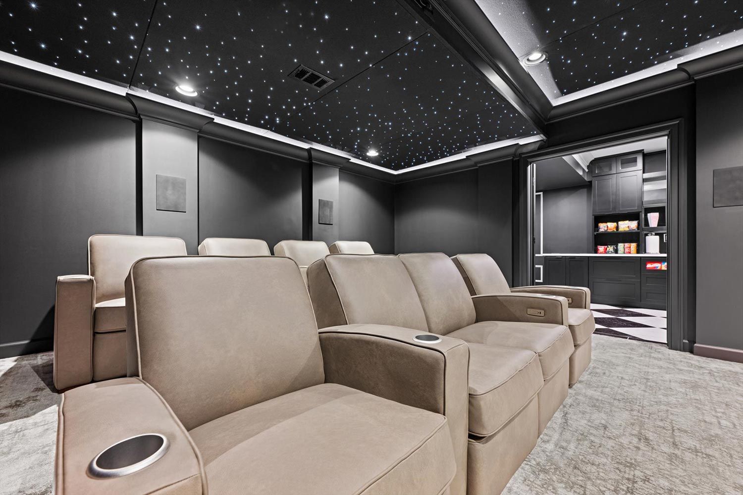 Comfortable home theater seating arranged in rows, facing a large projection screen with a starry ceiling, designed to enhance the cinematic experience.