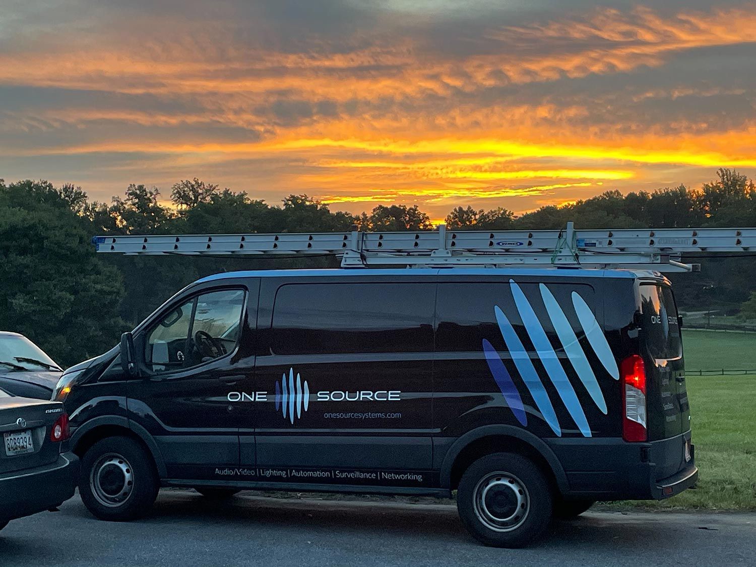 One Source Systems van with a sunset behind